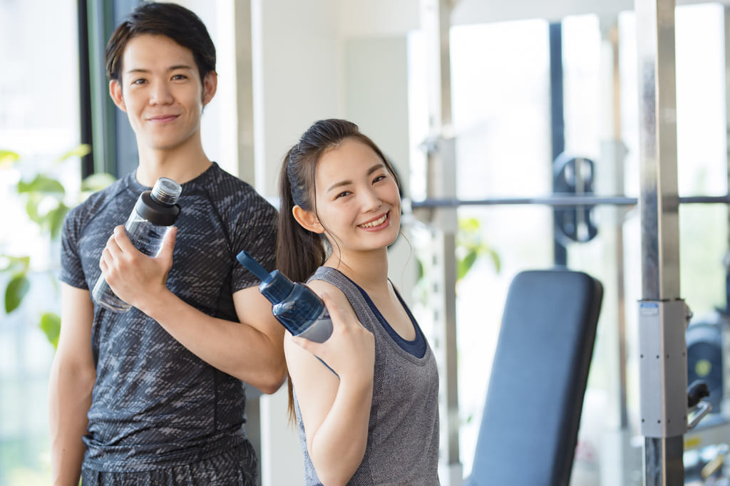 笑顔でダンベルを持つ男女の画像